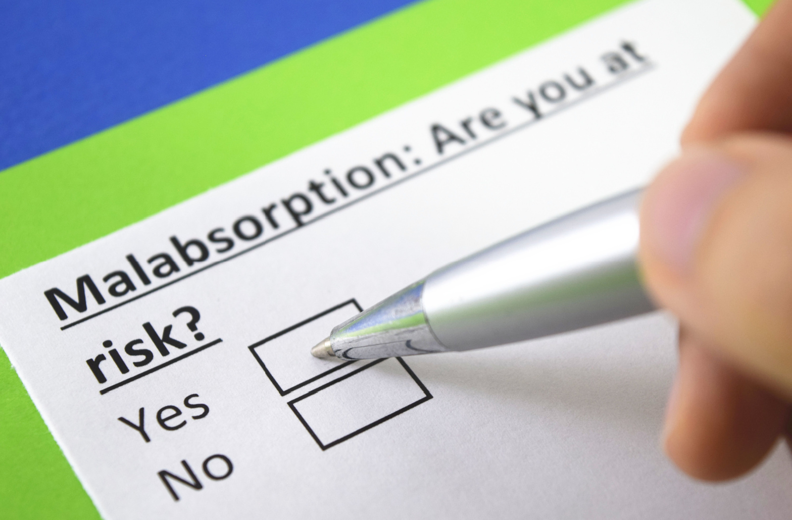 A close-up of someone using a pen to check a box labelled yes on a form asking if the person is at-risk for malabsorption, which can lead to anemia.