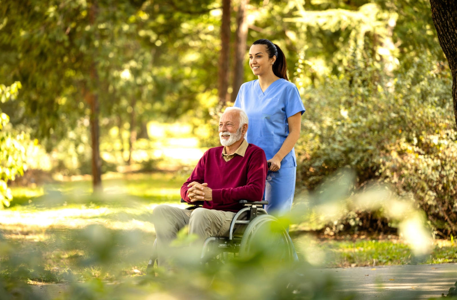 Healthcare aide pushing man in wheelchair.