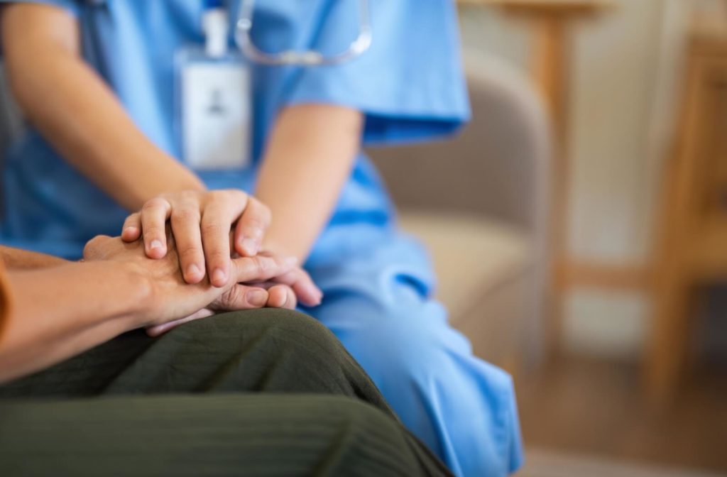 A close-up image of a caregiver's hands as they support a senior with dementia after a move to assisted living.