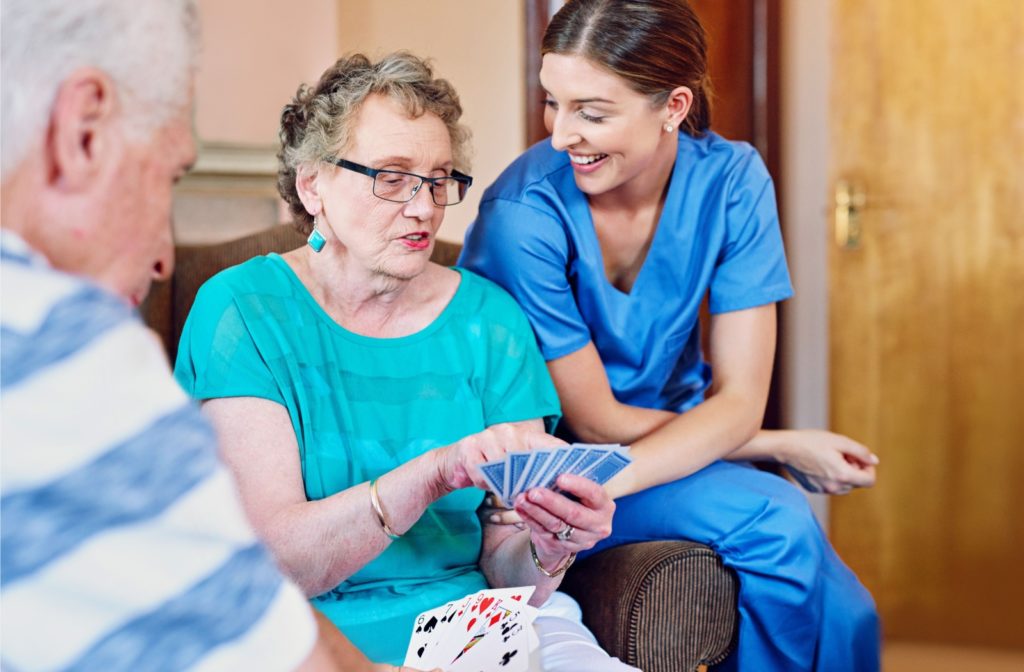 A caregiver and resident playing a card game together in an assisted living community.