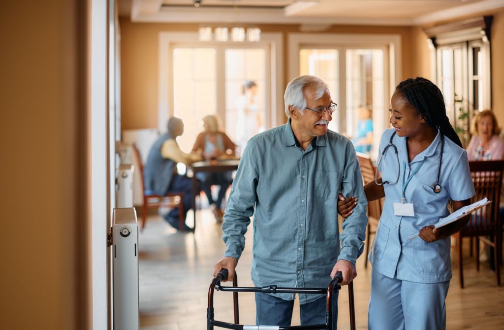 Caregiver assisting senior resident with their walker in an assisted living community.