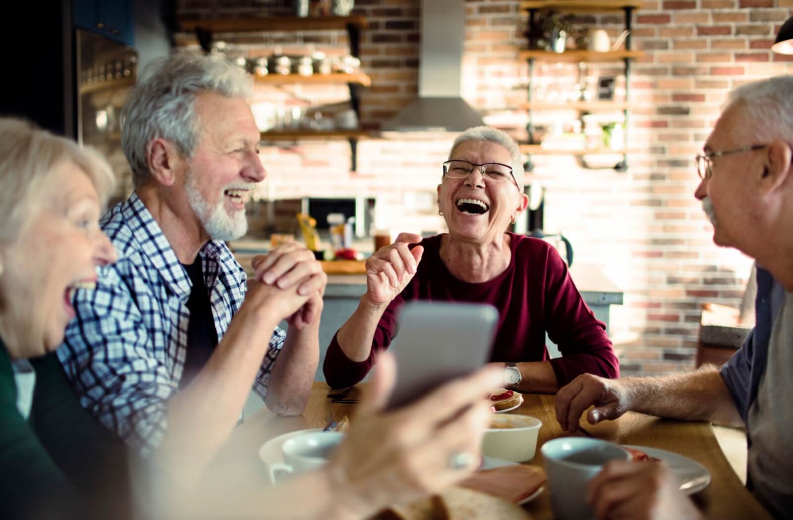 A group of seniors laughing over breakfast, eating together in senior living to boost their appetite.