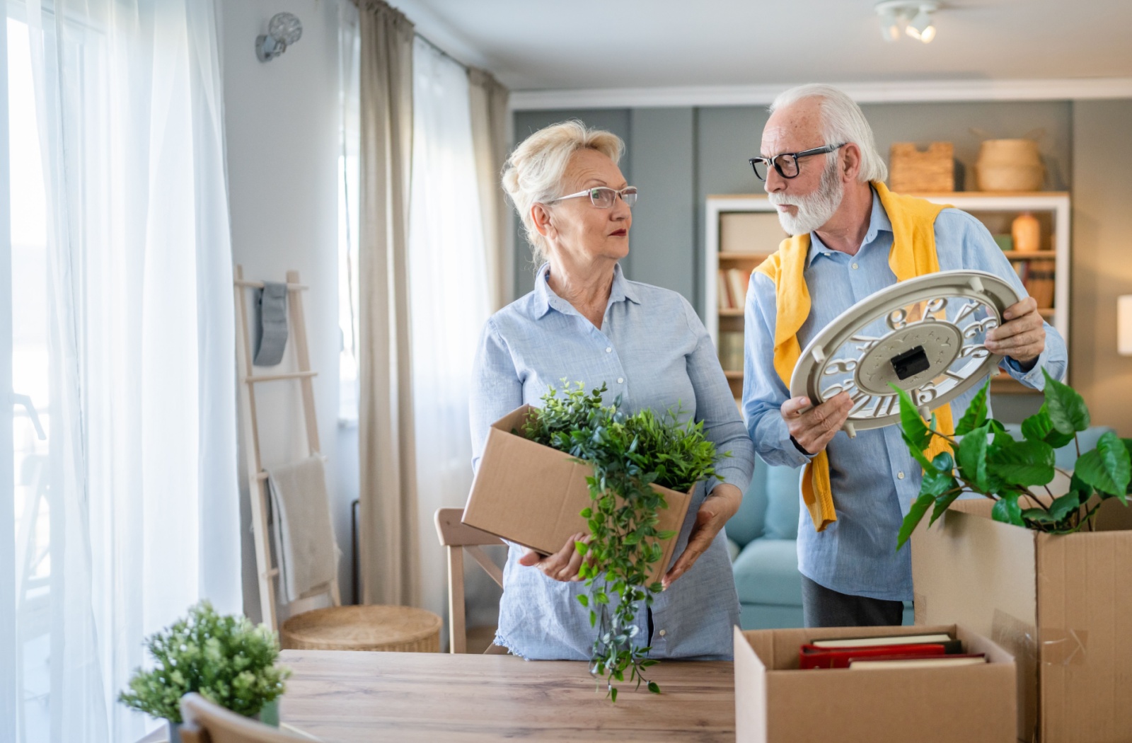A senior couple discussing their move and packing up old belongings in a bright, colorful setting.