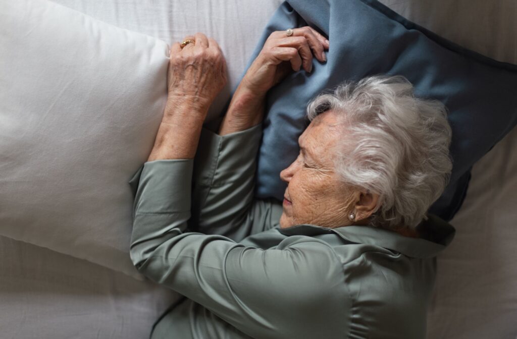 Senior resting in bed with a calm expression in a softly lit bedroom.