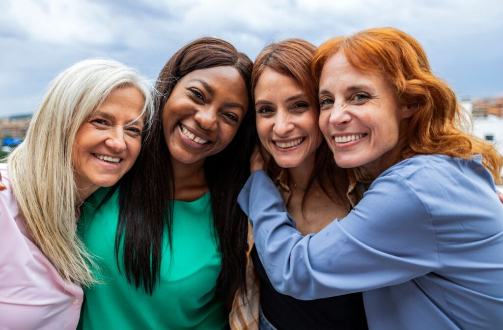 A group of four friends of varying ages hugging while outside.