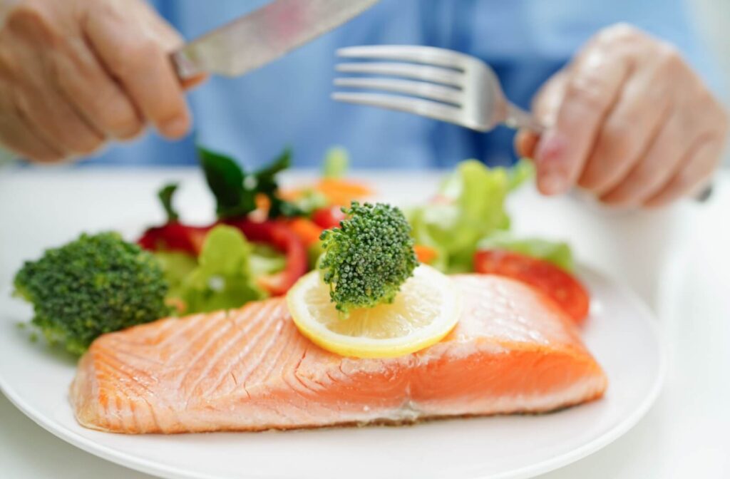 Grilled salmon with lemon broccoli and leafy greens on senior's plate