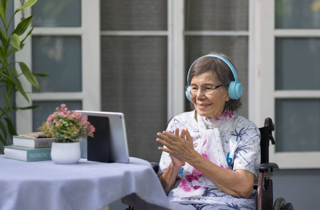 A senior with dementia spends time outdoors listening to music on a tablet with headphones as part of regular music therapy