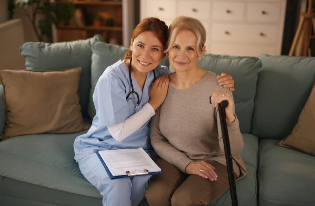 A nurse smiles with a senior holding a cane, helping with rehabilitation in respite care after an injury
